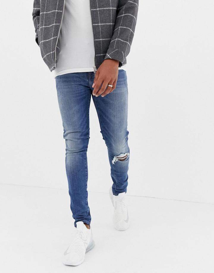 Asos Design 12.5oz Super Skinny Jeans In Mid Wash Blue With Knee Rip