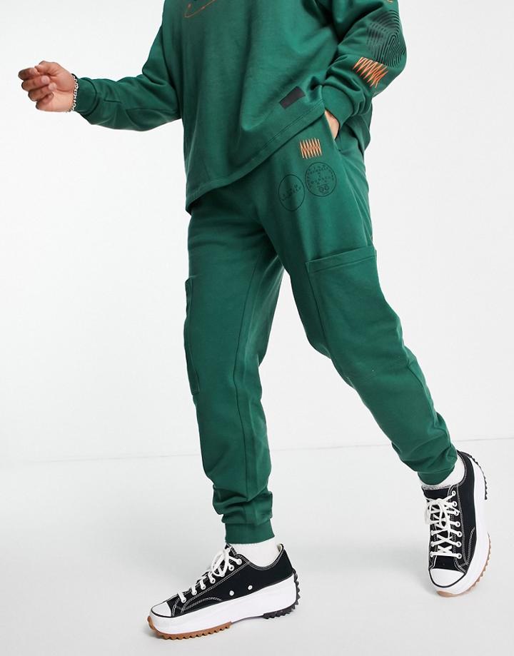Asos Design Matching Tapered Joggers With Cargo Pockets And Multi Placement Outdoors Prints-green